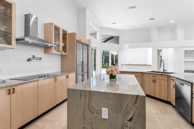 kitchen with stainless steel appliances, wall chimney range hood, a kitchen island, and glass insert cabinets