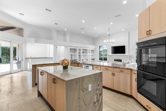 kitchen with open floor plan, light brown cabinetry, light stone counters, and a spacious island