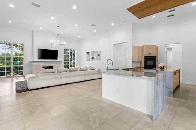 kitchen with light stone counters, a fireplace, open floor plan, light brown cabinetry, and pendant lighting