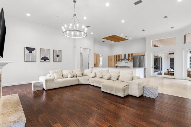 living area featuring visible vents, wood finished floors, a high ceiling, crown molding, and recessed lighting