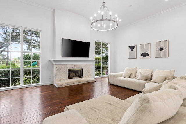 living area featuring ornamental molding, a high end fireplace, dark wood finished floors, and an inviting chandelier