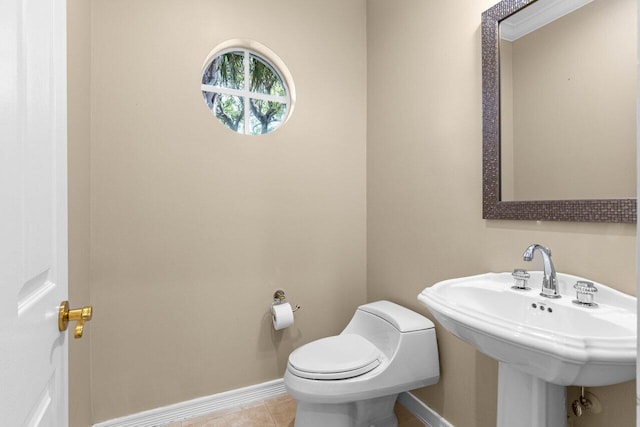 bathroom with toilet, baseboards, a sink, and tile patterned floors