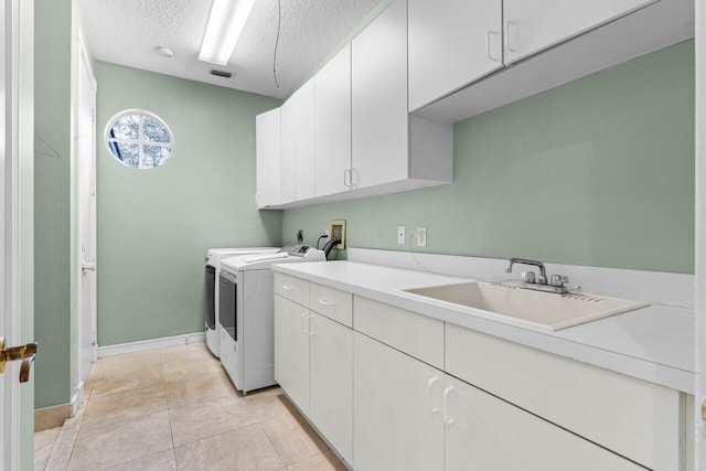 clothes washing area with a textured ceiling, light tile patterned floors, a sink, cabinet space, and washer and clothes dryer