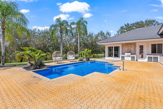 view of pool with area for grilling, fence, a grill, a fenced in pool, and a patio area