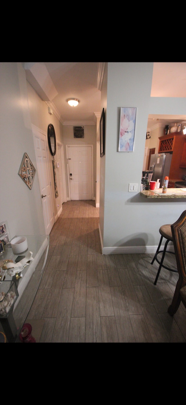 hall featuring ornamental molding, wood finish floors, and baseboards