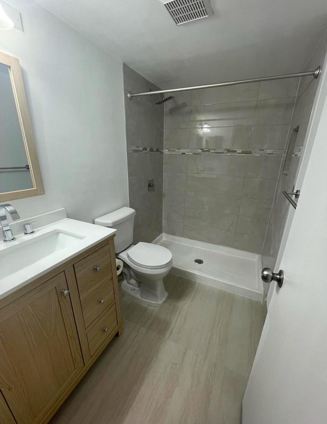 full bathroom with visible vents, toilet, a shower stall, vanity, and wood finished floors