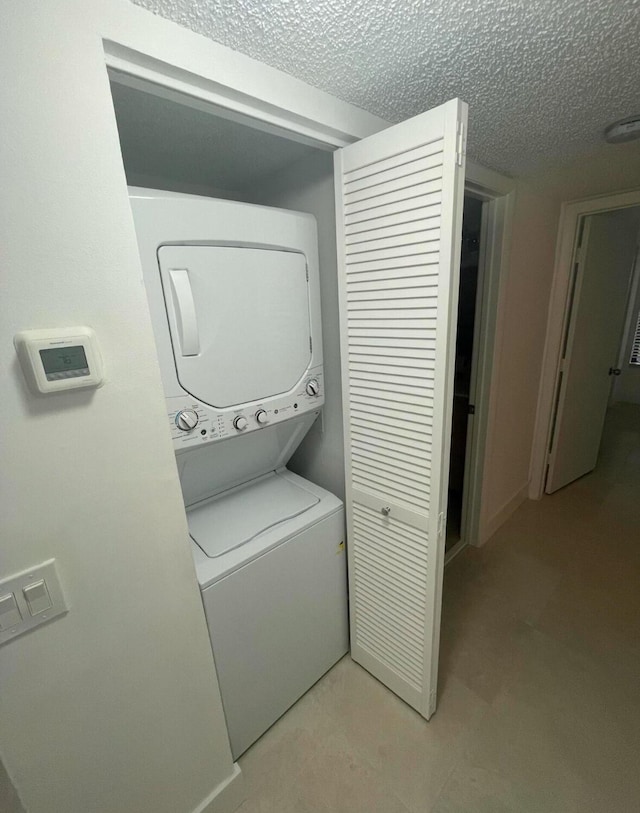 laundry room with a textured ceiling, stacked washer and dryer, and laundry area