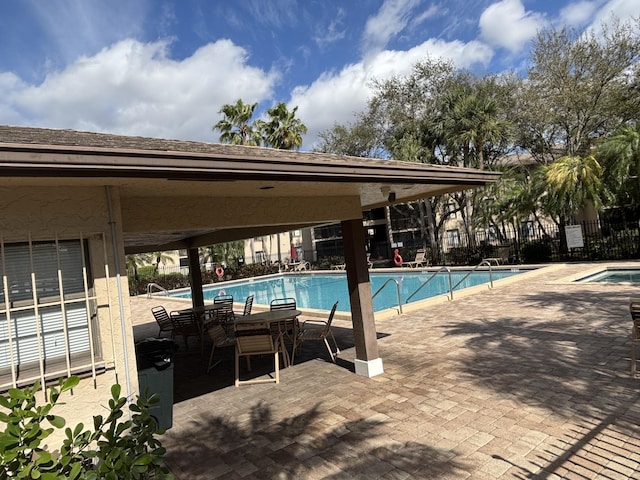 community pool with a patio area and fence