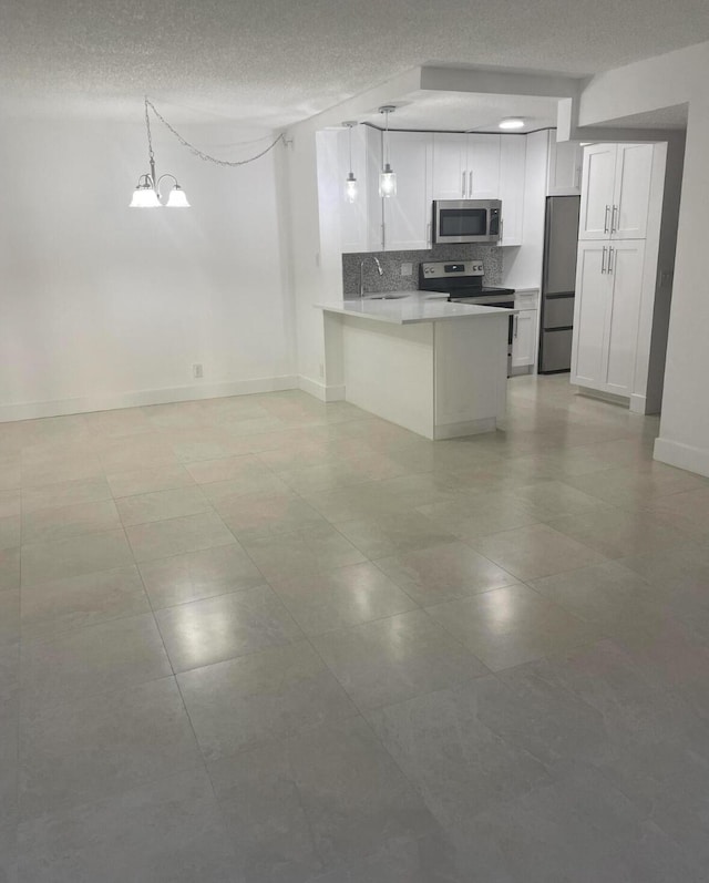 kitchen featuring open floor plan, white cabinetry, stainless steel appliances, and decorative light fixtures