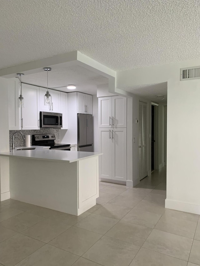 kitchen featuring stainless steel appliances, visible vents, white cabinetry, light countertops, and pendant lighting