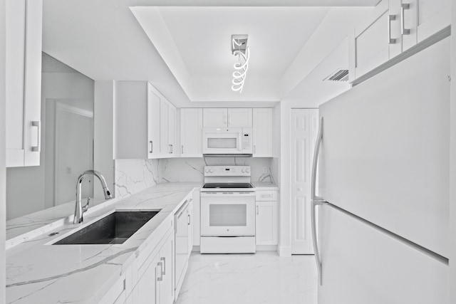 kitchen featuring white appliances, a sink, white cabinets, marble finish floor, and light stone countertops