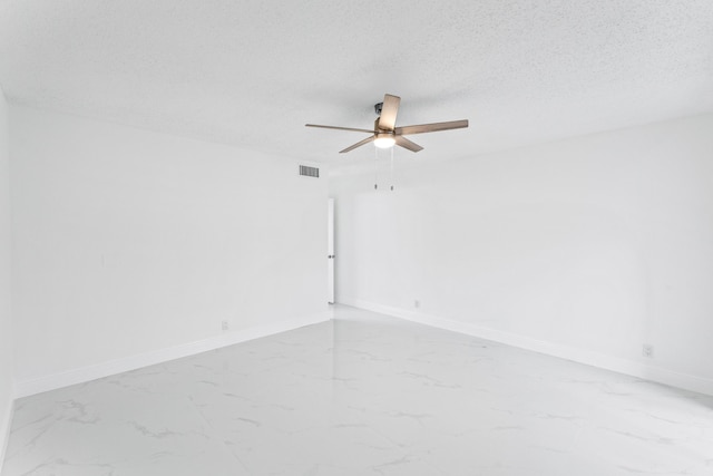 unfurnished room featuring marble finish floor, visible vents, a textured ceiling, and baseboards