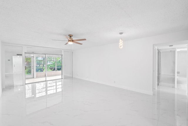 spare room with a textured ceiling, marble finish floor, a ceiling fan, and baseboards