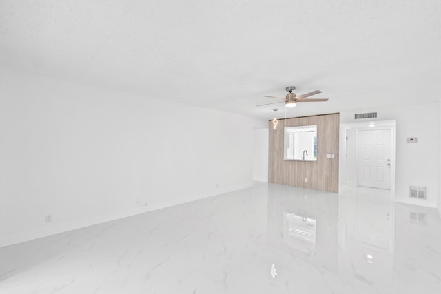 empty room featuring marble finish floor, baseboards, visible vents, and a ceiling fan