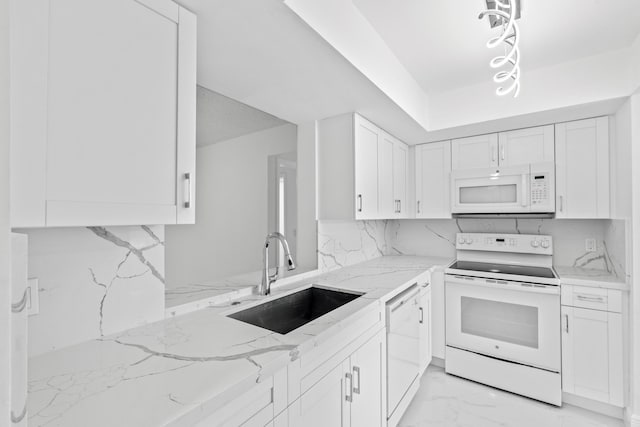 kitchen with light stone counters, white appliances, a sink, white cabinets, and decorative backsplash