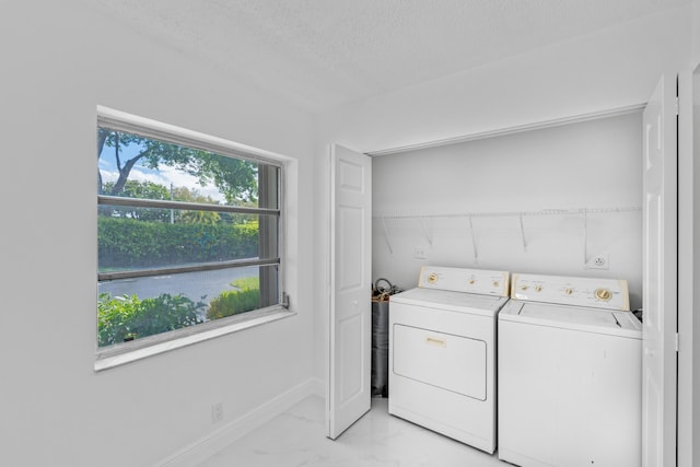 washroom featuring laundry area, a water view, marble finish floor, a textured ceiling, and washer and dryer