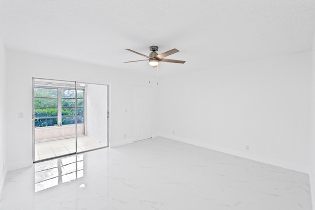 spare room featuring marble finish floor, ceiling fan, and baseboards