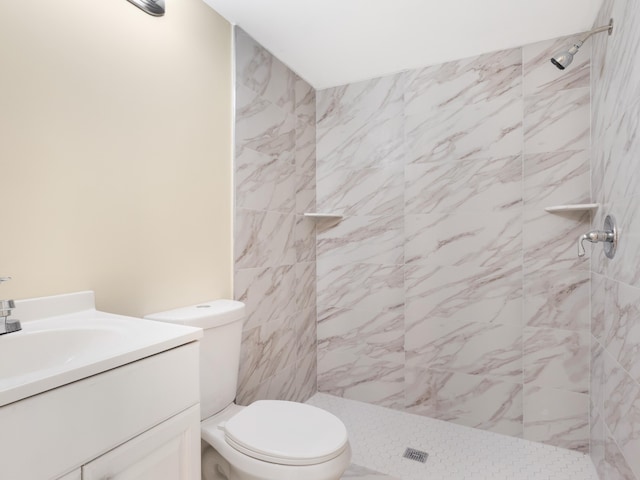 bathroom featuring toilet, vanity, and a tile shower