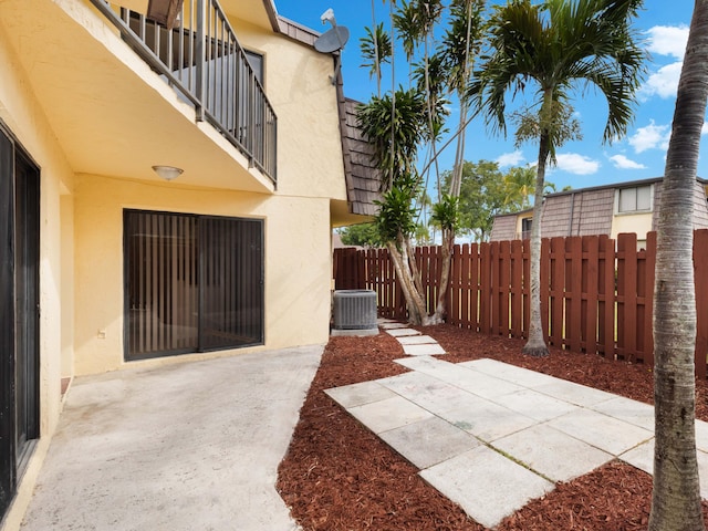 view of patio with central AC, a balcony, and fence