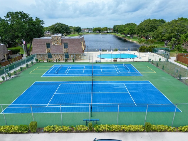 view of sport court with a community pool, fence, and a water view