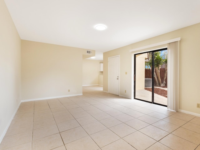 empty room with light tile patterned floors, visible vents, and baseboards