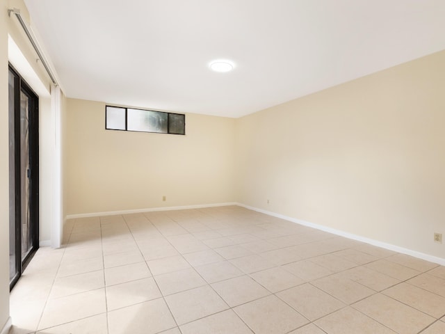 empty room featuring baseboards and light tile patterned flooring