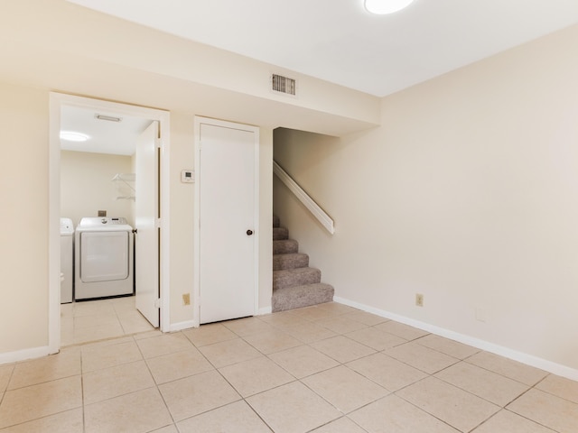 empty room featuring visible vents, independent washer and dryer, light tile patterned floors, baseboards, and stairs