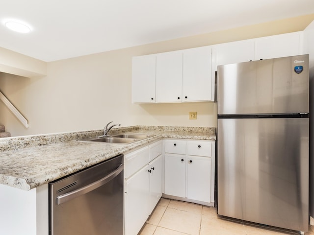 kitchen with light tile patterned floors, appliances with stainless steel finishes, white cabinetry, and a sink