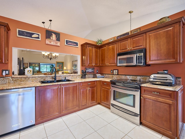 kitchen featuring hanging light fixtures, appliances with stainless steel finishes, vaulted ceiling, and a sink