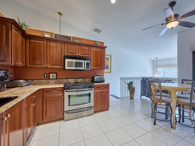 kitchen with light stone counters, decorative light fixtures, light tile patterned floors, stainless steel appliances, and lofted ceiling