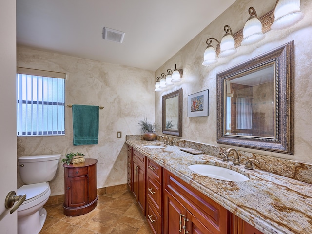 bathroom with toilet, double vanity, visible vents, and a sink