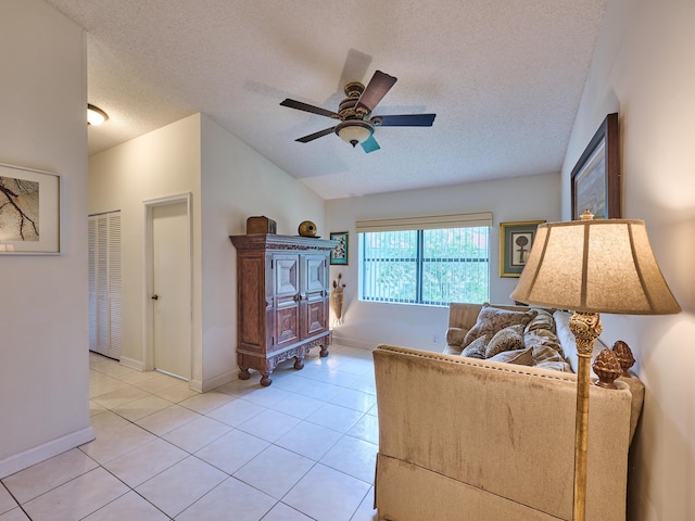 living area featuring baseboards, ceiling fan, vaulted ceiling, a textured ceiling, and light tile patterned flooring