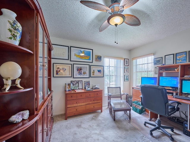 office space with a ceiling fan, light colored carpet, a textured ceiling, and baseboards