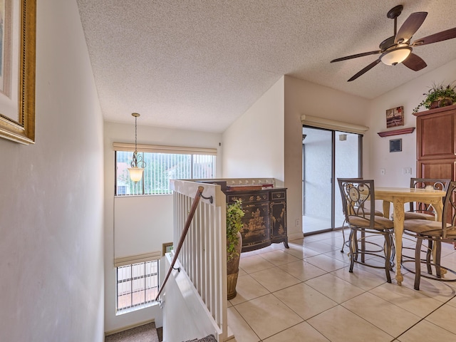 interior space with light tile patterned floors, a textured ceiling, and an upstairs landing