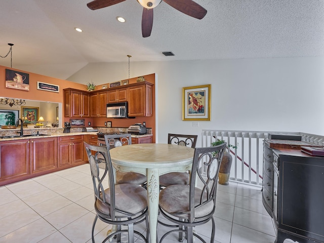 kitchen with decorative light fixtures, visible vents, stainless steel microwave, light tile patterned flooring, and a sink