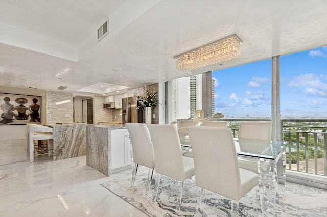 dining area featuring marble finish floor, visible vents, and floor to ceiling windows