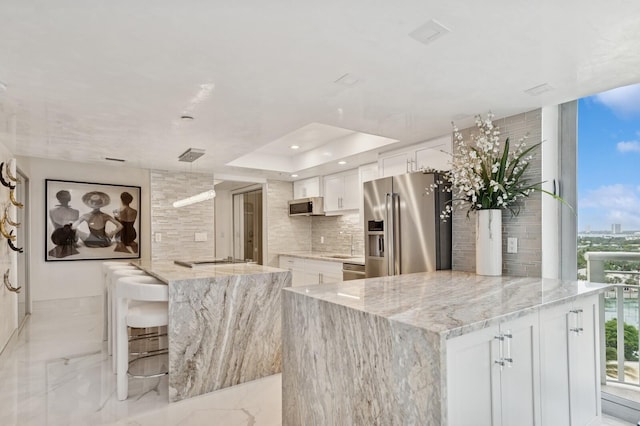 kitchen featuring tasteful backsplash, white cabinets, a kitchen island, marble finish floor, and stainless steel appliances