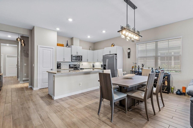 dining room featuring light wood-type flooring, baseboards, and recessed lighting