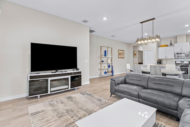 living room featuring baseboards, recessed lighting, visible vents, and light wood-style floors