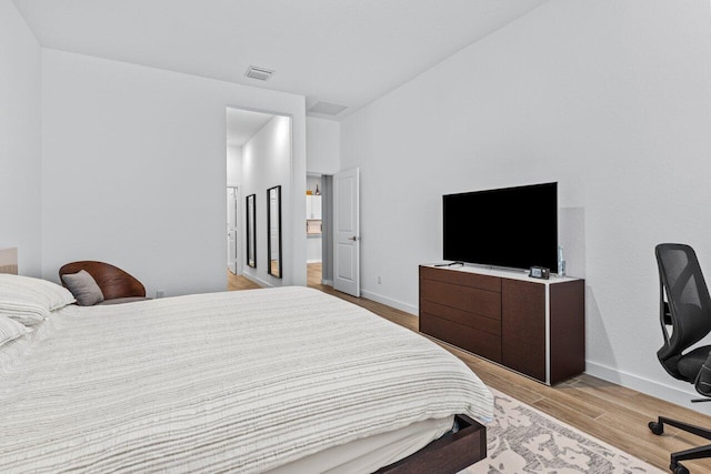 bedroom featuring light wood finished floors, visible vents, and baseboards