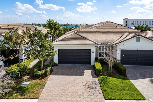 single story home with a garage, decorative driveway, and a tiled roof