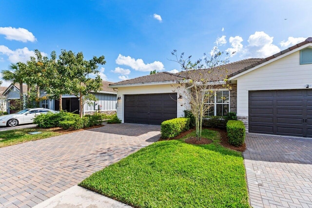 single story home featuring an attached garage, stone siding, decorative driveway, and a front yard