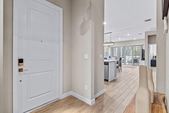 foyer entrance with visible vents, baseboards, light wood-style flooring, a chandelier, and recessed lighting