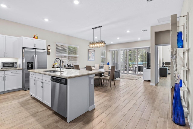 kitchen featuring stainless steel appliances, light stone counters, light wood-type flooring, and a sink