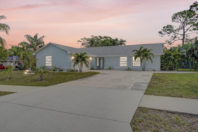 view of front of home featuring concrete driveway and a yard