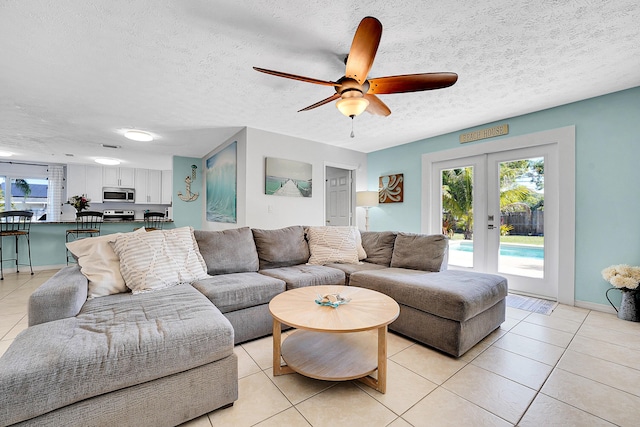 living area featuring light tile patterned floors, french doors, a textured ceiling, and a ceiling fan