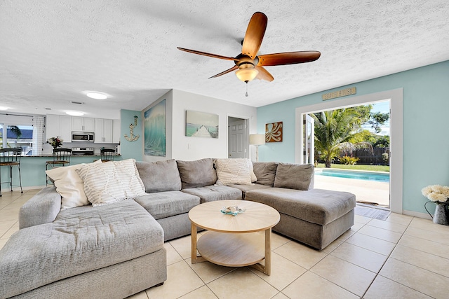 living area with light tile patterned floors, a textured ceiling, and a ceiling fan