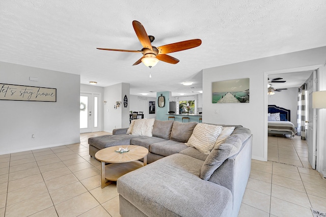 living room featuring a textured ceiling, baseboards, a ceiling fan, and light tile patterned flooring