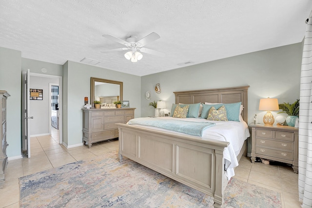 bedroom featuring light tile patterned floors, a textured ceiling, visible vents, baseboards, and a ceiling fan