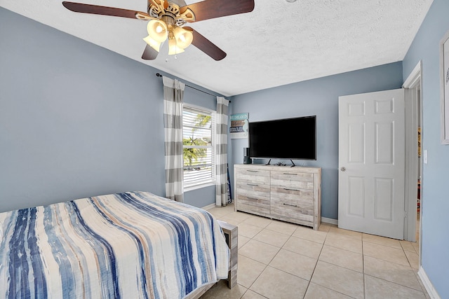 bedroom with light tile patterned floors, ceiling fan, a textured ceiling, and baseboards